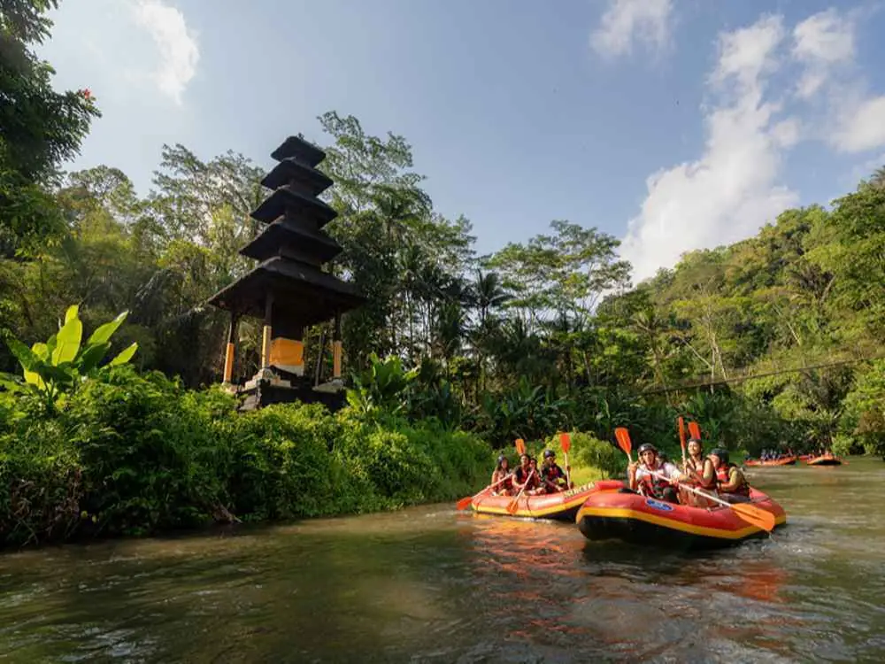 Surya Bintang Adventures rafts passing tropical scenery and a riverside shrine on the Ayung River