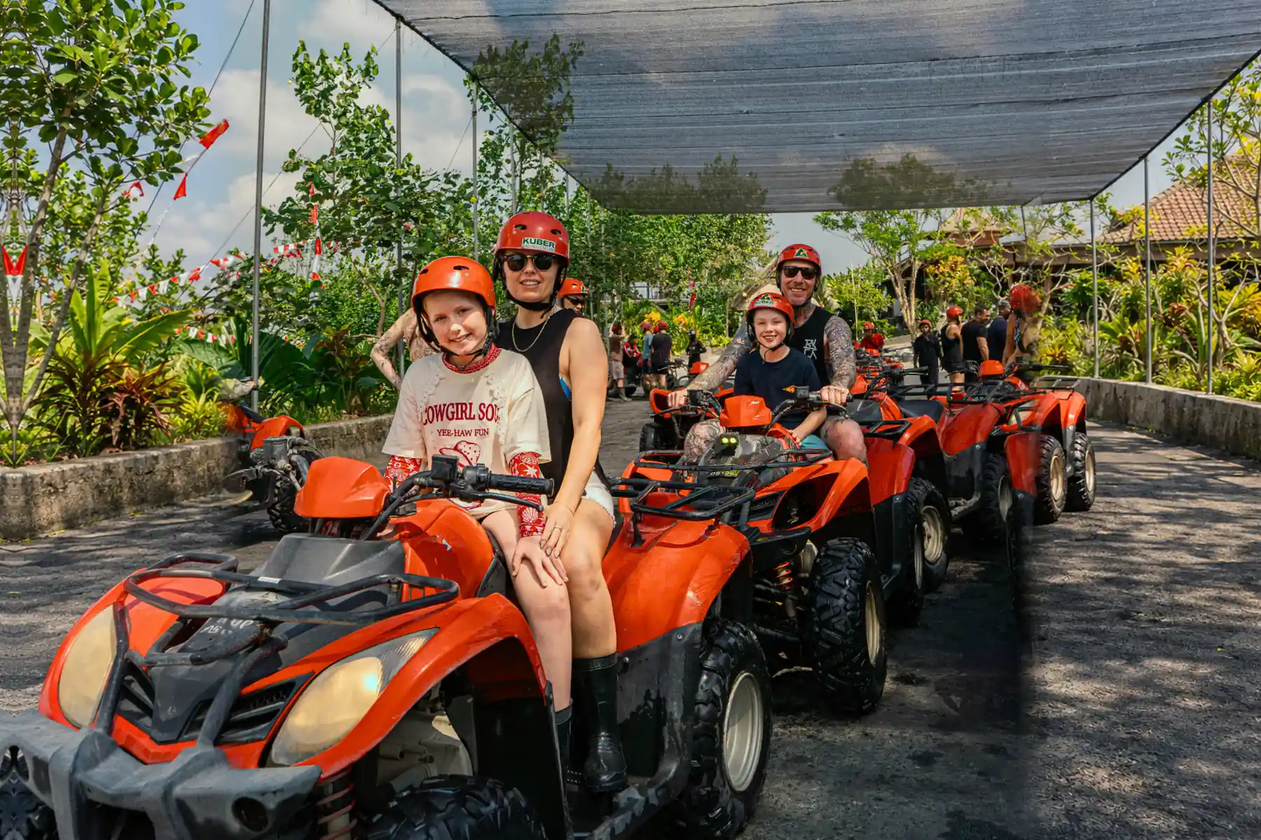 Family wearing red helmets on tandem ATVs at Kuber Bali Adventure
