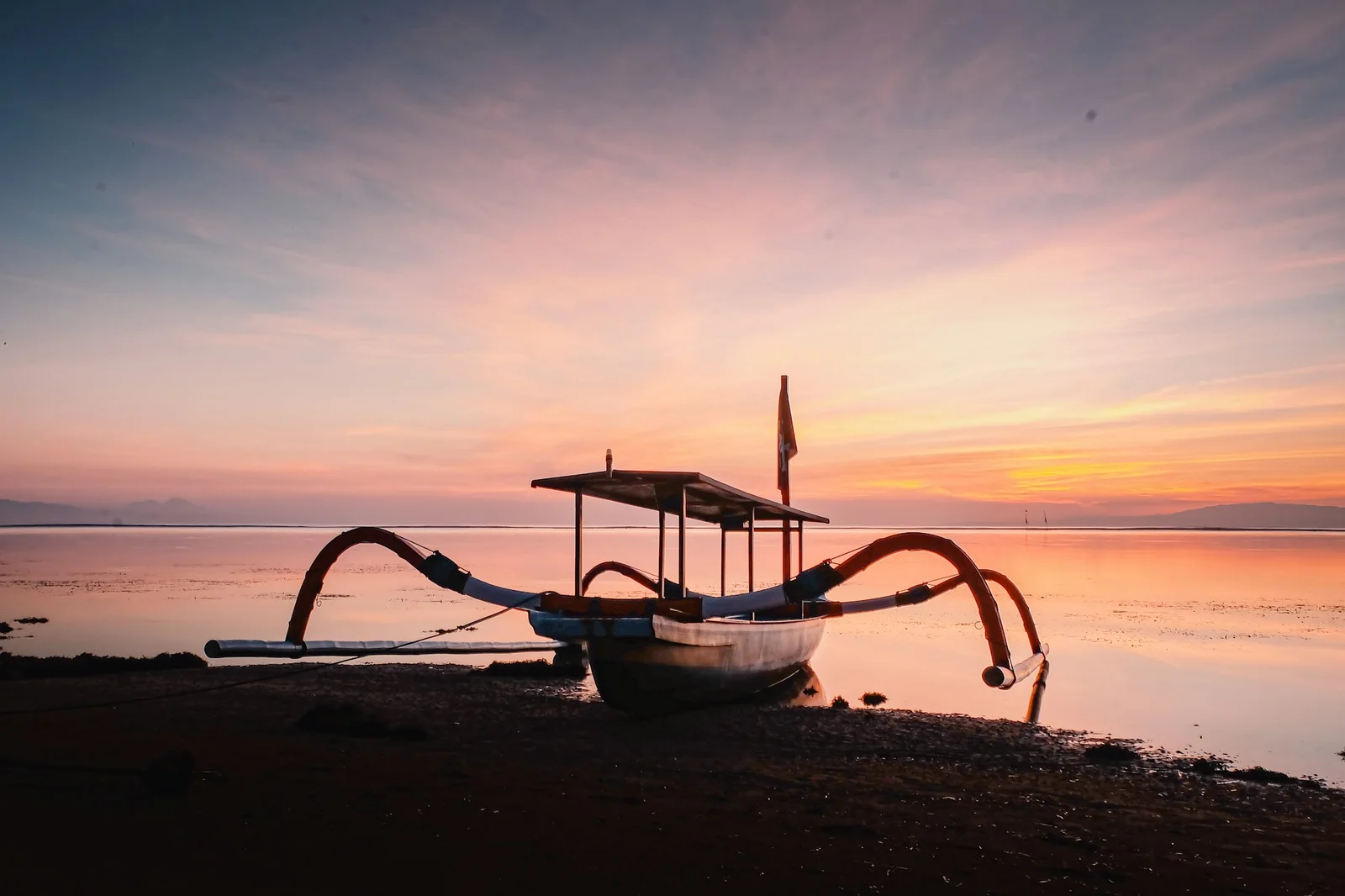 Sunrise over Sanur Beach in Bali with traditional boats on the water